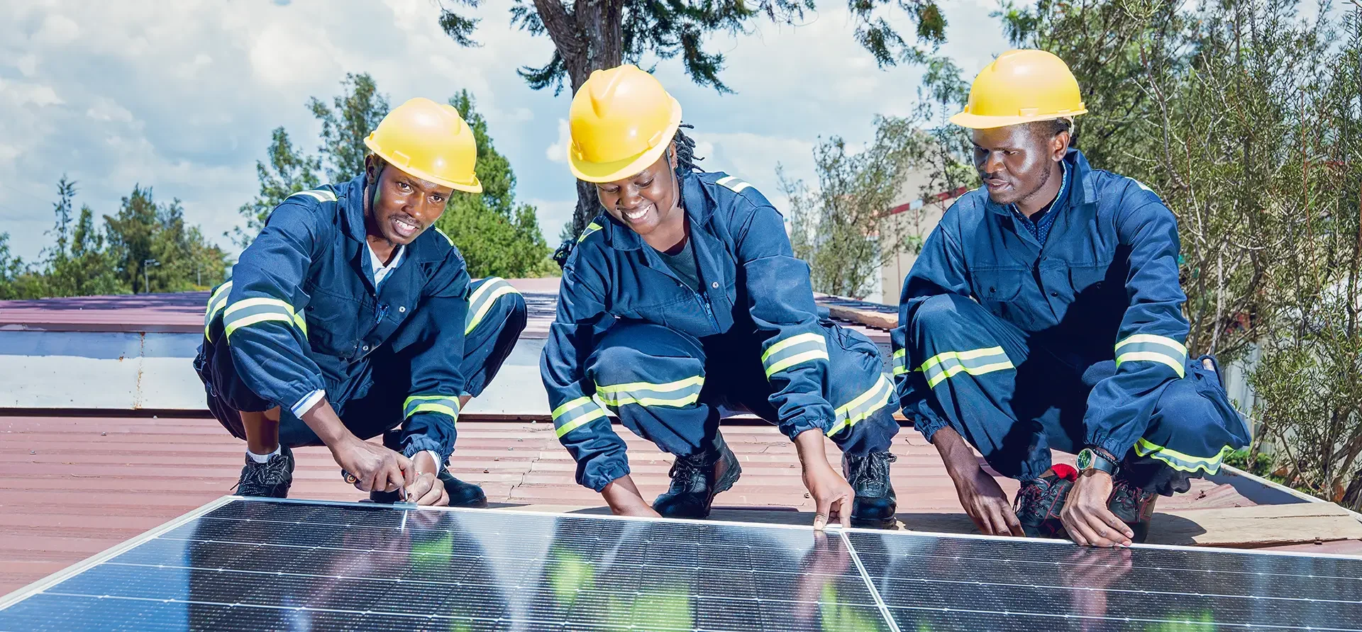 Trainees in safety gear aligning and fastening a rooftop solar panel during WTS Foundation hands-on training in Kenya