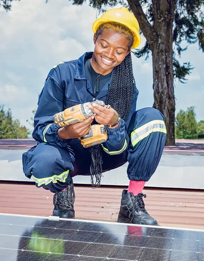 Student in safety gear using a drill while installing a solar panel during a technical course
